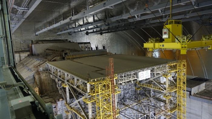 Inneres des New Safe Confinement, vorne eine Stabilisierungskonstruktion, dahinter der alte Sarkophag