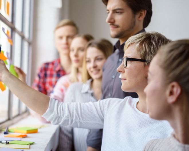 Menschen stehen vor einer Wand mit Post-it-Zetteln