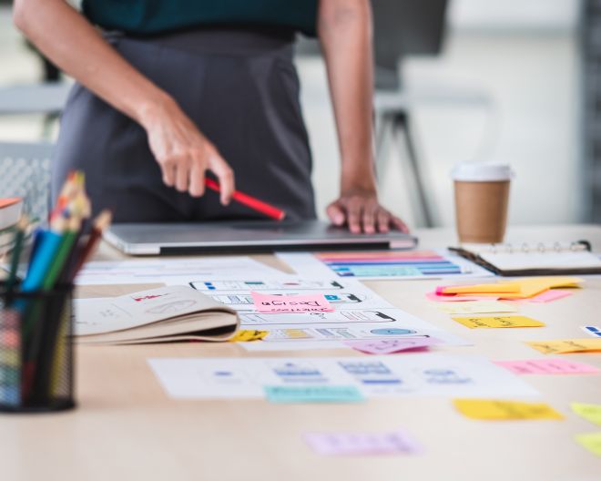 chließen Ux Entwickler und ui Designer Brainstorming über mobile App-Schnittstelle Wireframe-Design auf Tisch mit Kunden-Brief und Farbcode in modernen Büro. 