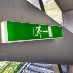 Grün leuchtenden Flucht Ausgangsschild auf weißen Betonwand