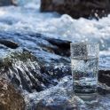 Mit Wasser gefülltes Trinkglas steht in einem Fluss