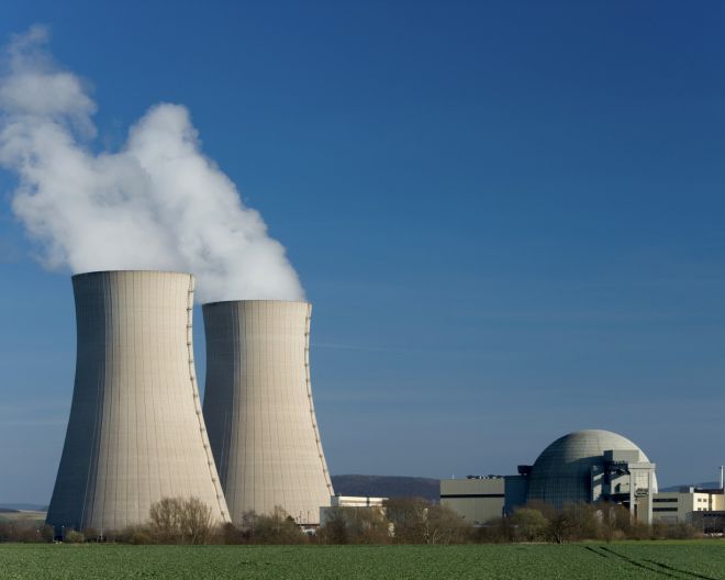 Das deutsche Kernkraftwerk Grohnde mit zwei dampfenden Kühltürmen.