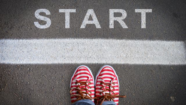 Ein Mensch schaut auf seine Schuhe herunter, die vor einer Startlinie stehen