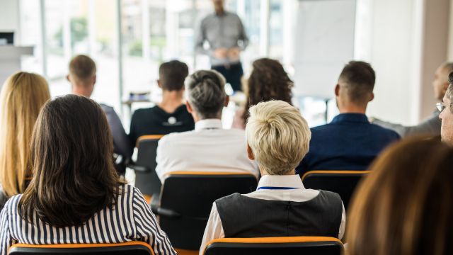 Rückansicht von Menschen, die an einem Seminar im Sitzungssaal teilnehmen