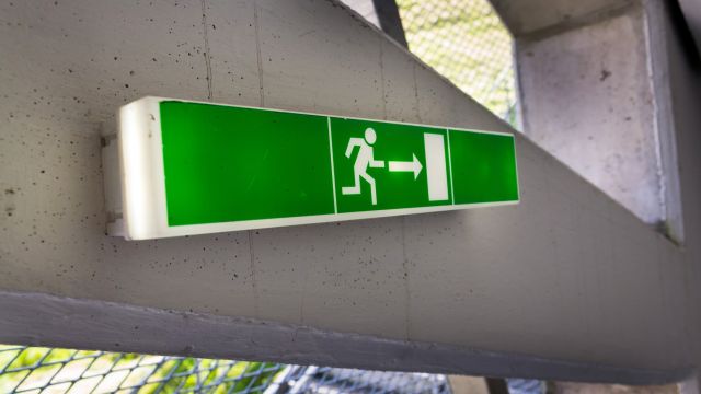 Nuklearer Notfallschutz Grün leuchtenden Flucht Ausgangsschild auf weißen Betonwand