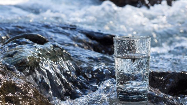 Mit Wasser gefülltes Trinkglas steht in einem Fluss