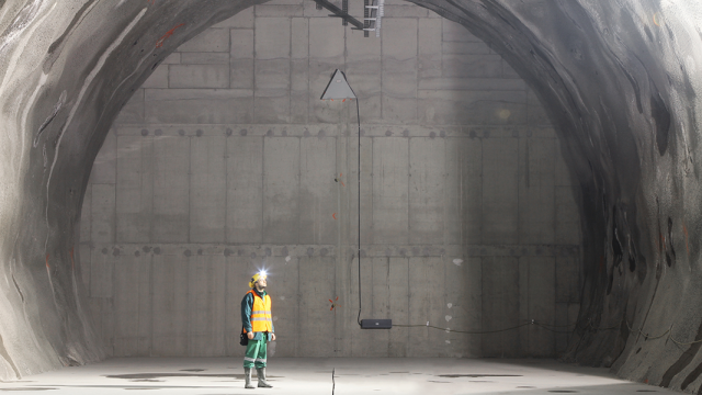 Mann Untertage vor einer großen Betonwand.